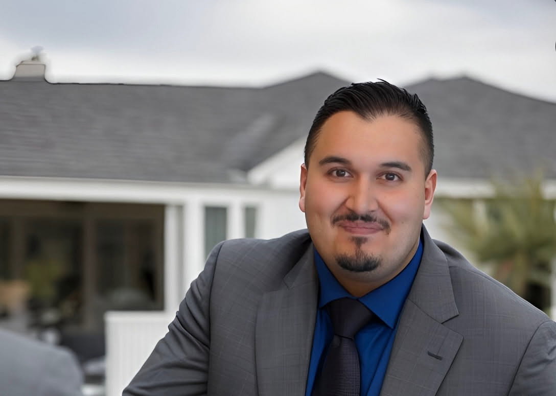 Oscar Sandoval, smiling in front of a home